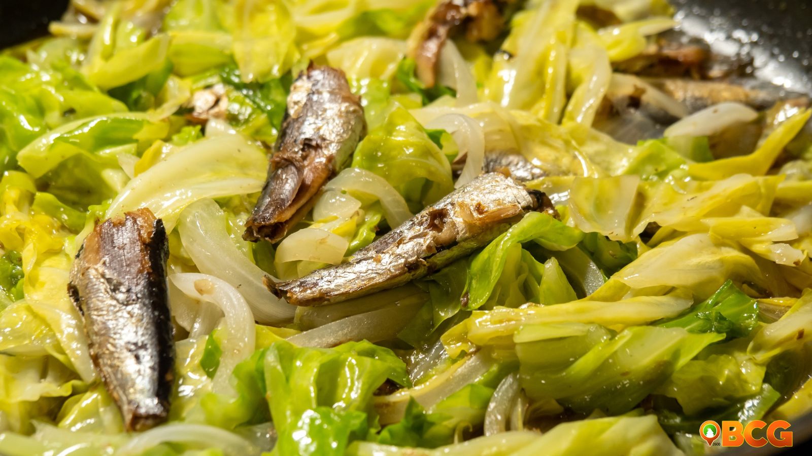 Ginisang Repolyo with sardines garnished with peppers and herbs, showcasing a delicious cabbage dish.